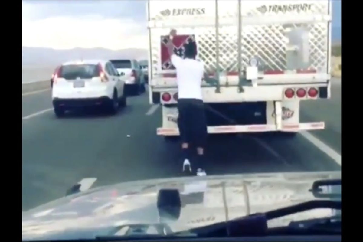Watch a man peel a confederate flag off of a moving truck in traffic.
