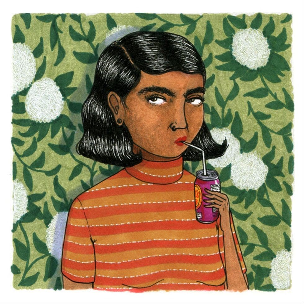 woman in striped orange shirt sipping soda through a straw against leafy background