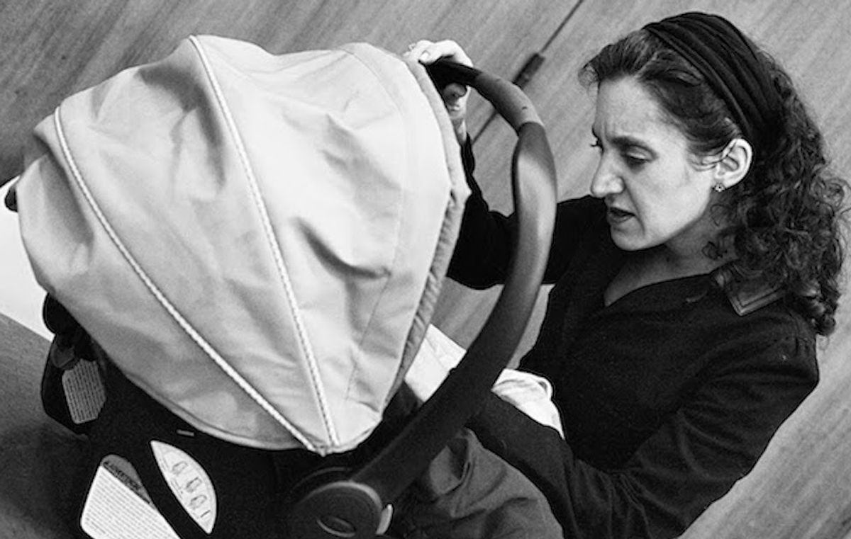 Black and white photo of woman looking into a baby carrier