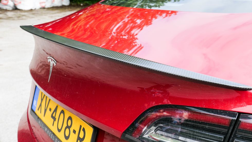 Photo of the carbon spoiler of a red Tesla Model 3 Performance