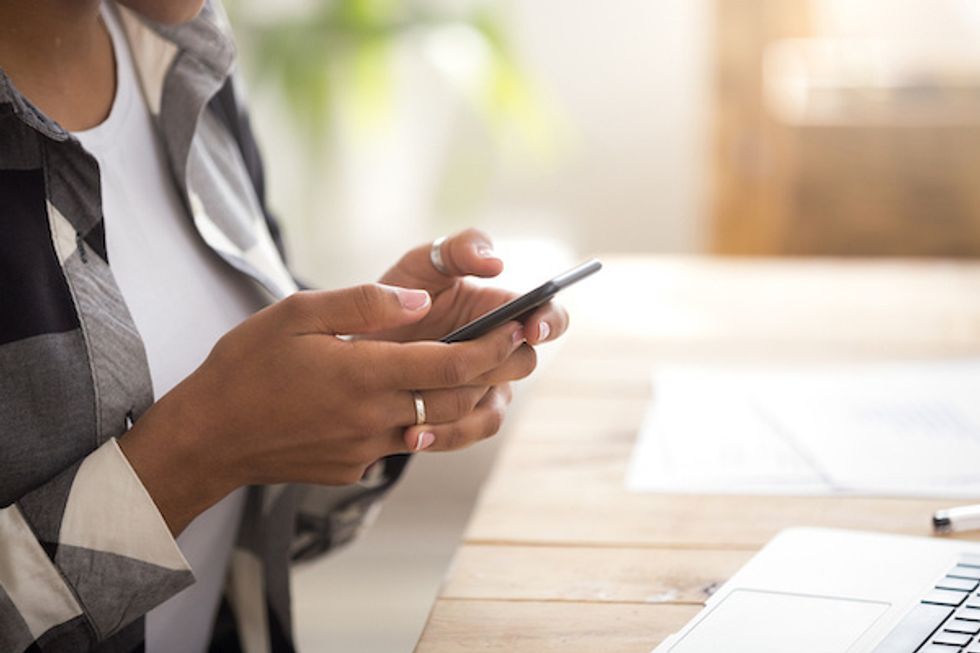 A woman holding a smartphone in her hands over a desk
