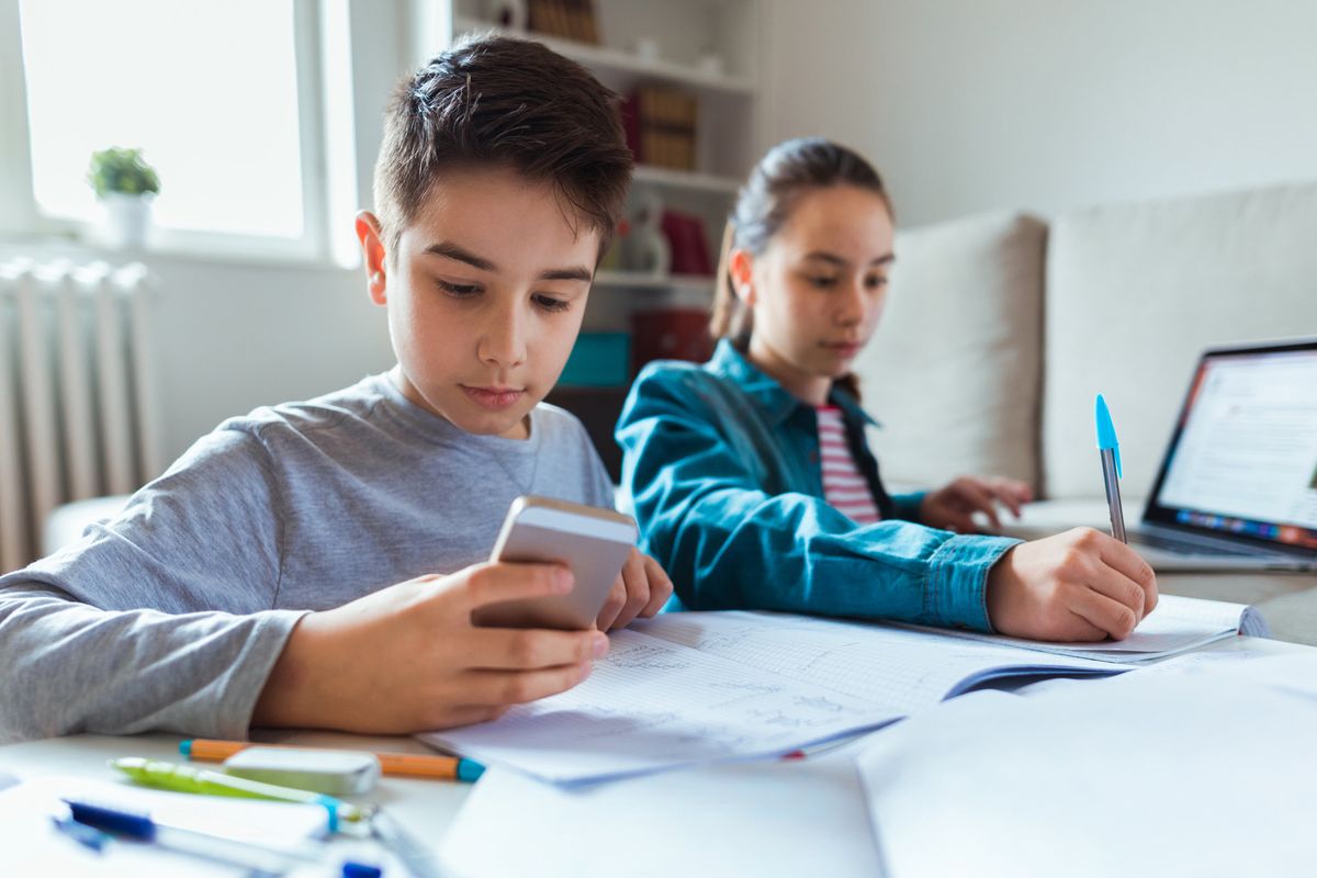 Stock image of children working with a smartphone and laptop