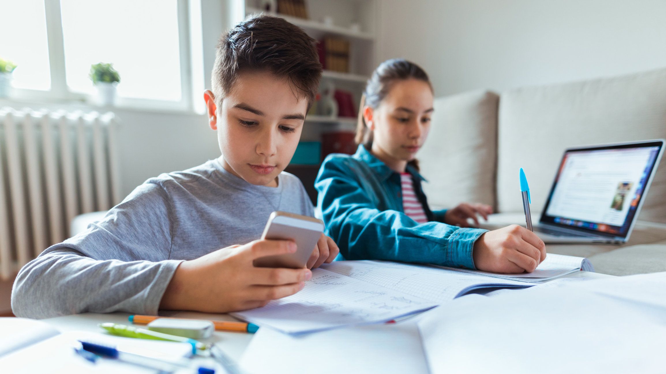 Stock image of children working with a smartphone and laptop