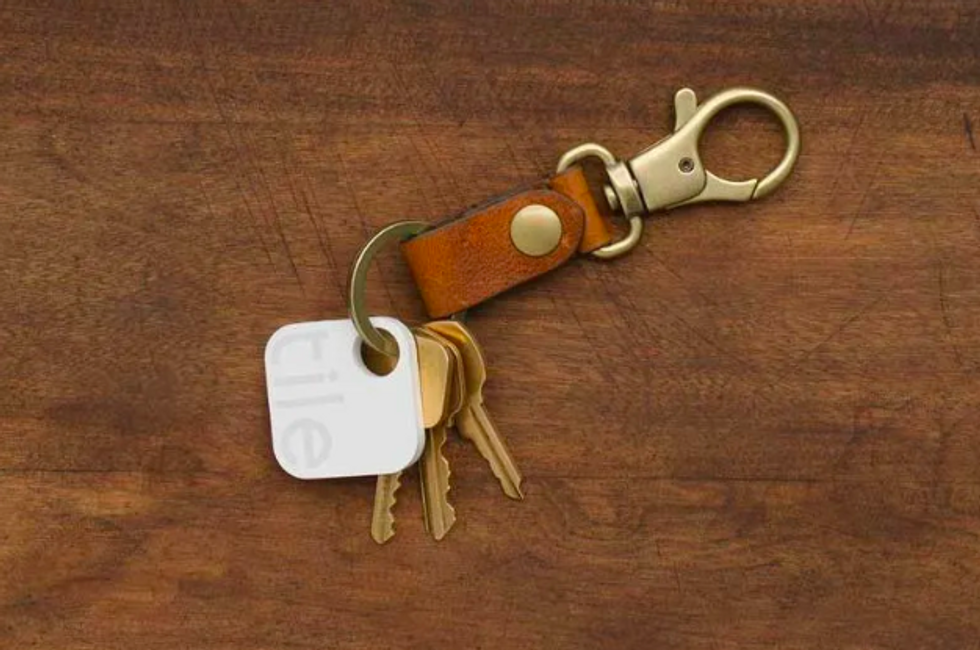 A photo of a Tile Bluetooth trackers on a leather key ring with keys