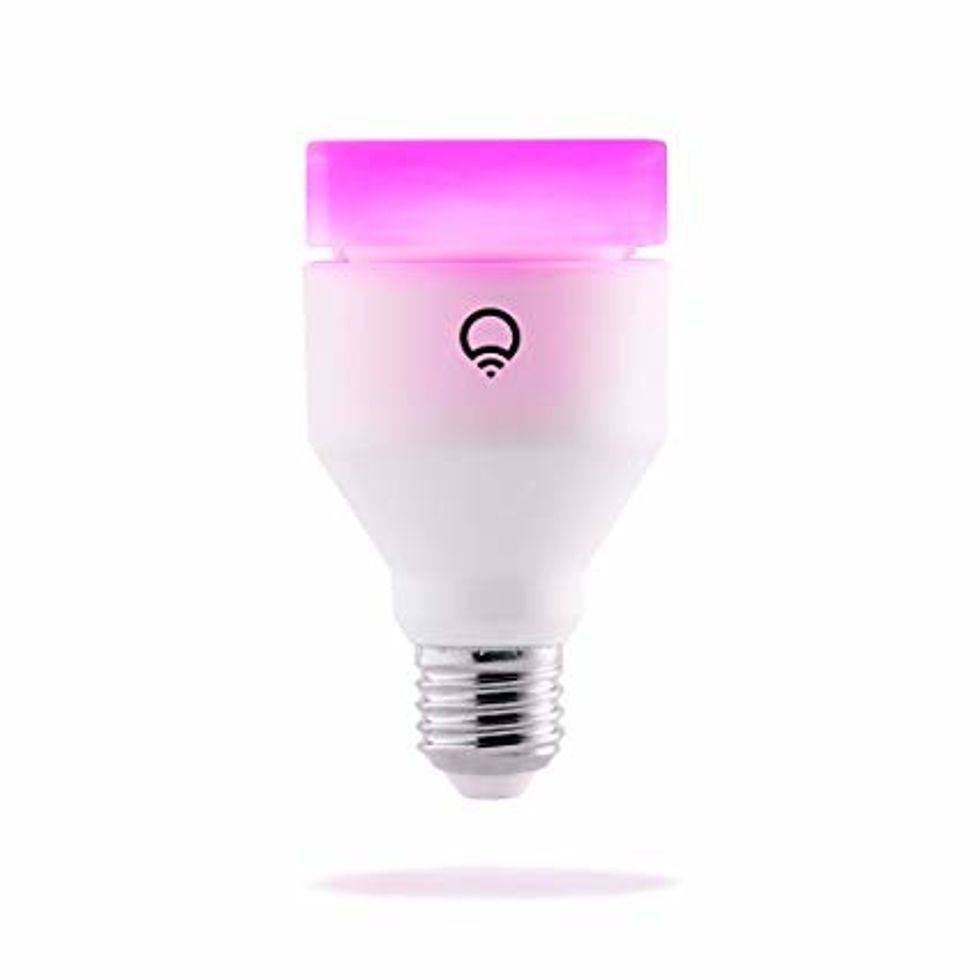 A smart light bulb from Lifx with a flat top and giving off a pink light