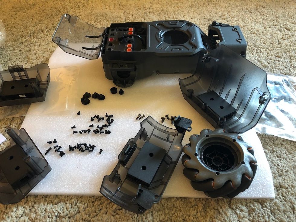 The pieces of a robot including a wheel, plastic covers and a car chassis
