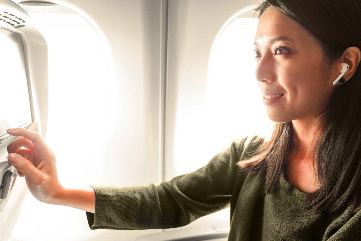 Photo of a woman using AirPods on a plane