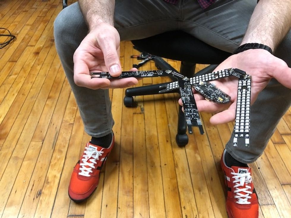 A man, wearing red shoes, holding the parts of a drone in his hands