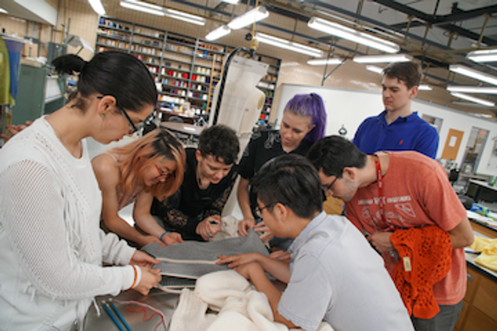 Students crowding around fabric on a table