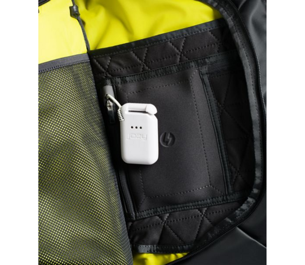 A white battery pack with the word "joey" on it, hanging from inside a loop on abag