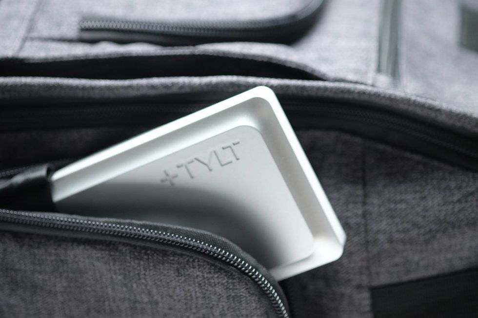 A small white plastic battery with the word "Tylt" on it inside a zippered pocket