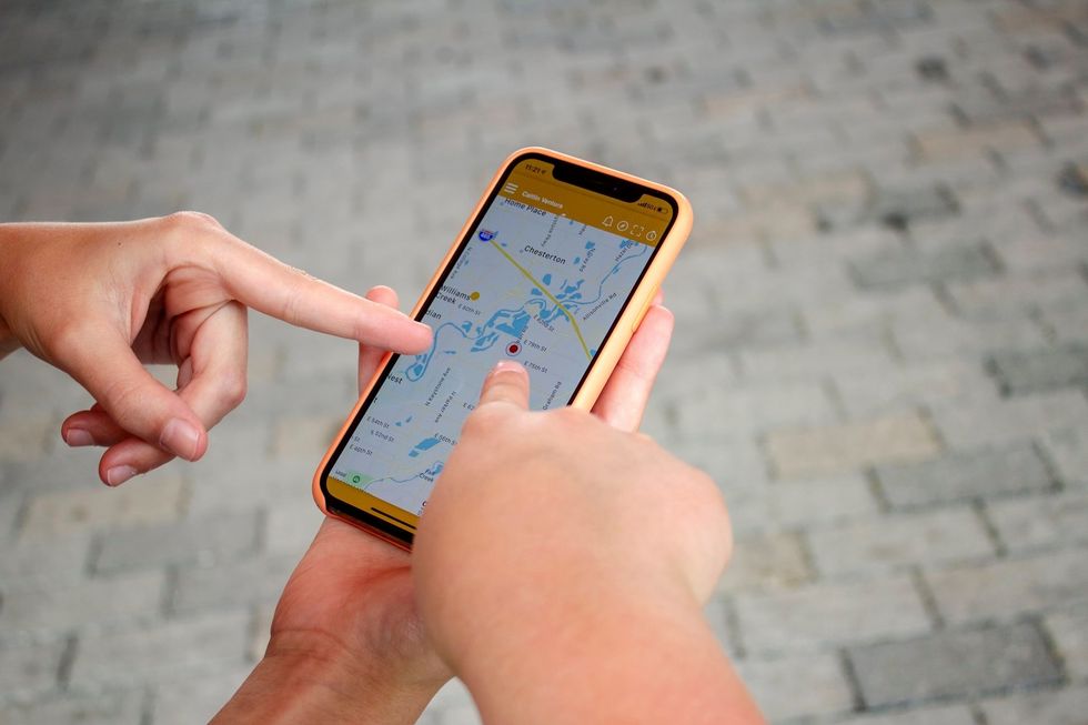 Multiple fingers pointing to a smartphone with a map on the screen