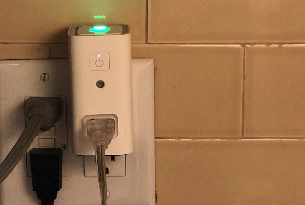 An Awair Glow C plugged into an outlet with a green light glowing at the top