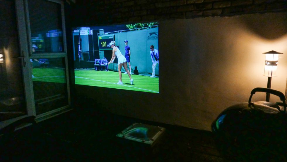 A projection of a tennis player on an outdoor wall