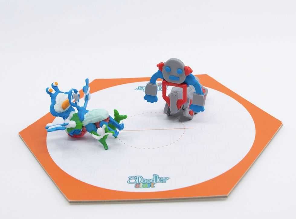 A paper hexagon, with two plastic multi-colored figures standing inside