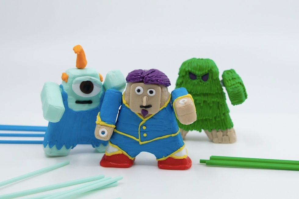 Three plastic figures, a one-eyed blue creature, a green-haired character and a person with a blue suit and purple hair
