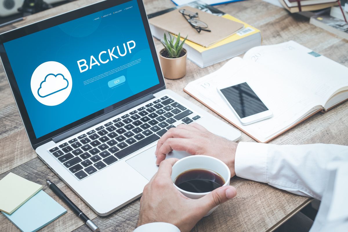 Stock image of a computer being backed up to the cloud