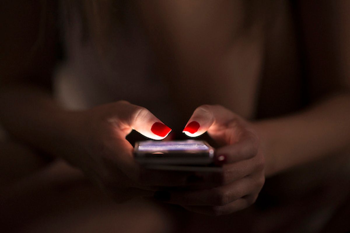 Someone wearing red fingernail polish, holding a smartphone in their hands