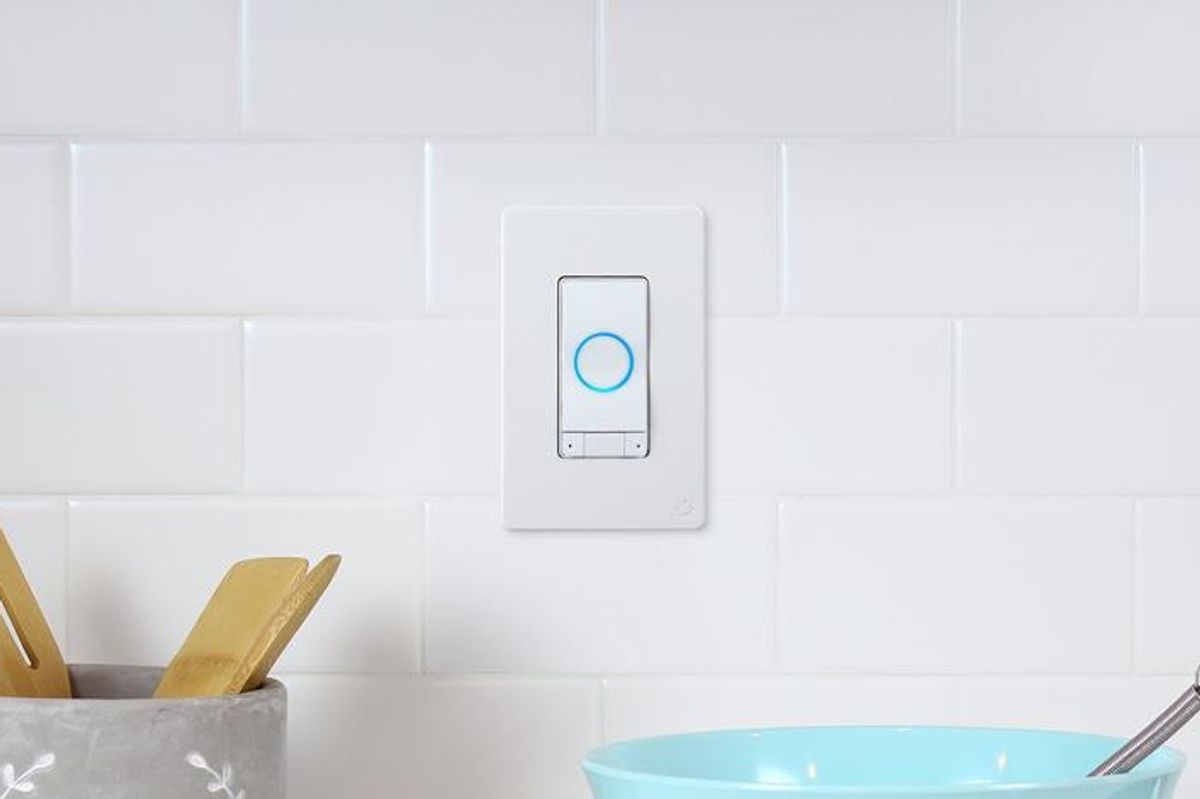 A white wall switch with a blue light circle in the middle on a white, tiled wall