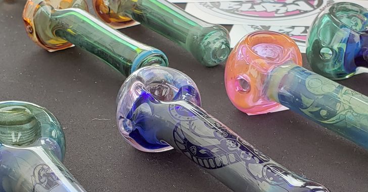 Image: Six glass pipes in assorted colors, each etched with a different design. The most prominent pipe is blue with a tribal design