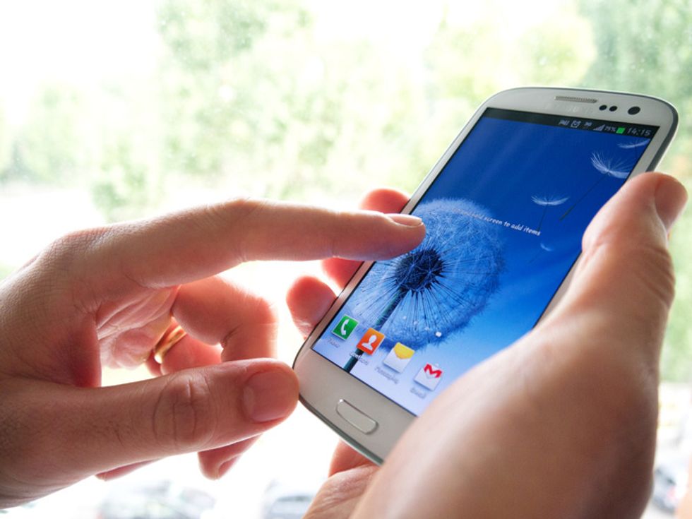 Two hands holding a smartphone with a flower on the screen