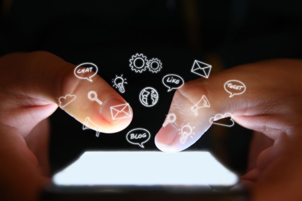 Two fingers typing on a smartphone with small icons over them
