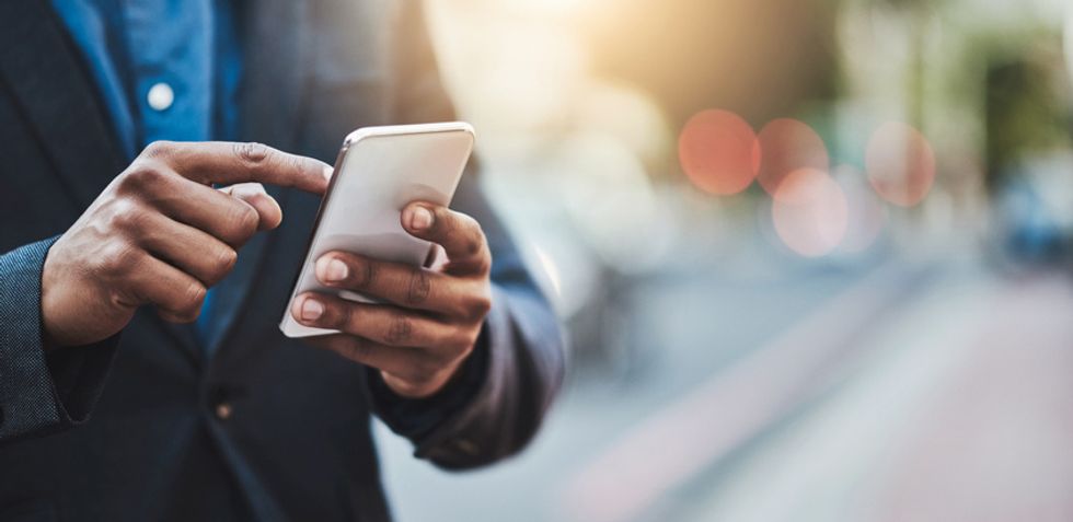Someone in a business suit holding a smartphone on the street