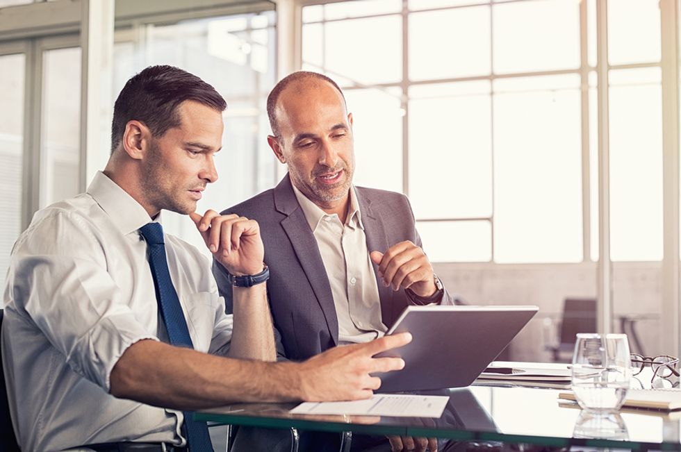 Male leader using his leadership skills by giving constructive feedback to a member of his team.