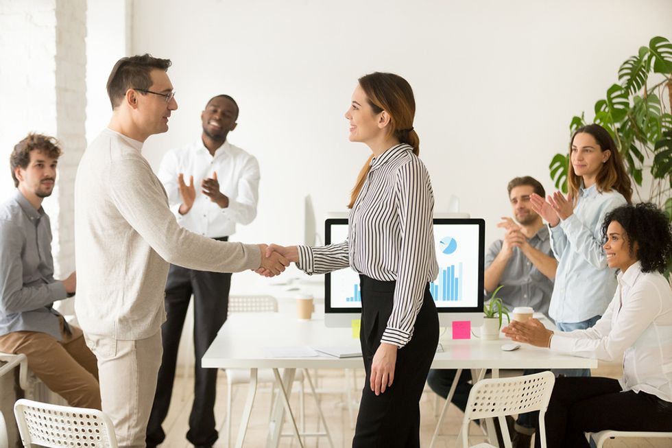 Manager congratulating a team member by shaking their hand at the office.