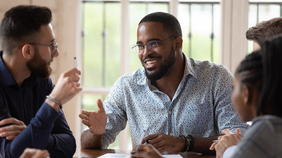 Male manager using his influential soft skills to meet with his team.