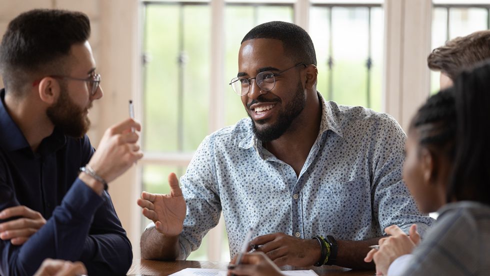 Male manager using his influential soft skills to meet with his team.