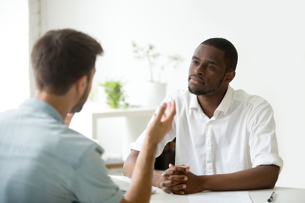 Male leader receiving constructive feedback in an office and thinking about how he can develop his leadership skills.