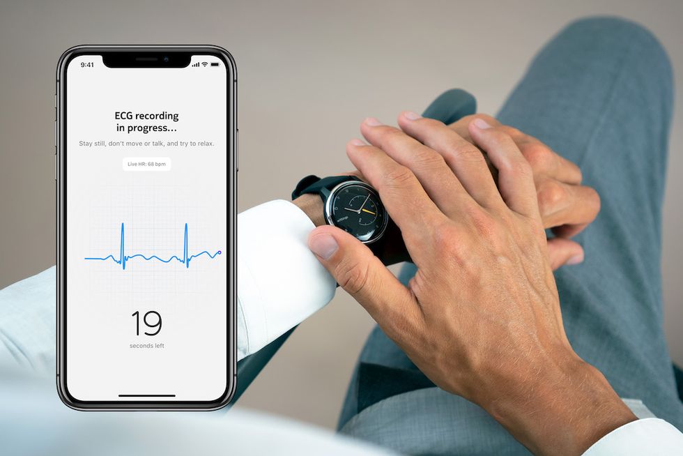 A hand pressed on a smartwatch, with a screenshot of a heart rhythm, with the number 19, seen