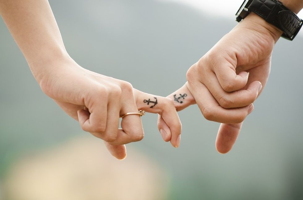 couple holding fingers with anchor tattoos