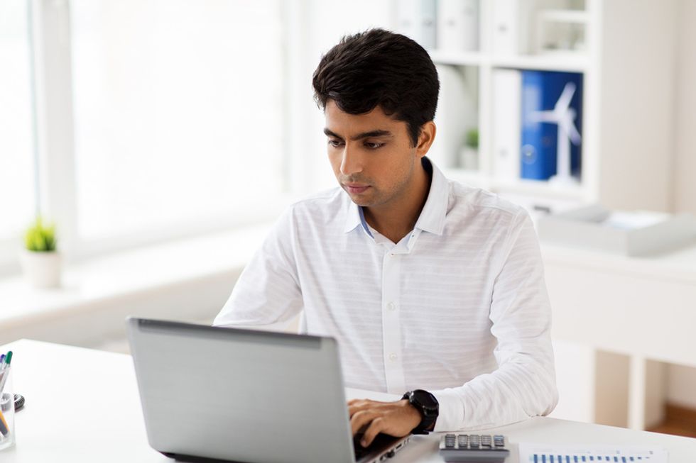 Man looking over his resume on the computer and formatting it to fit a leadership role.
