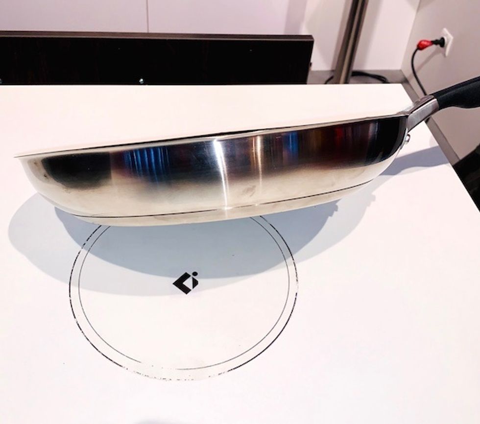 A frying pan over a white induction surface