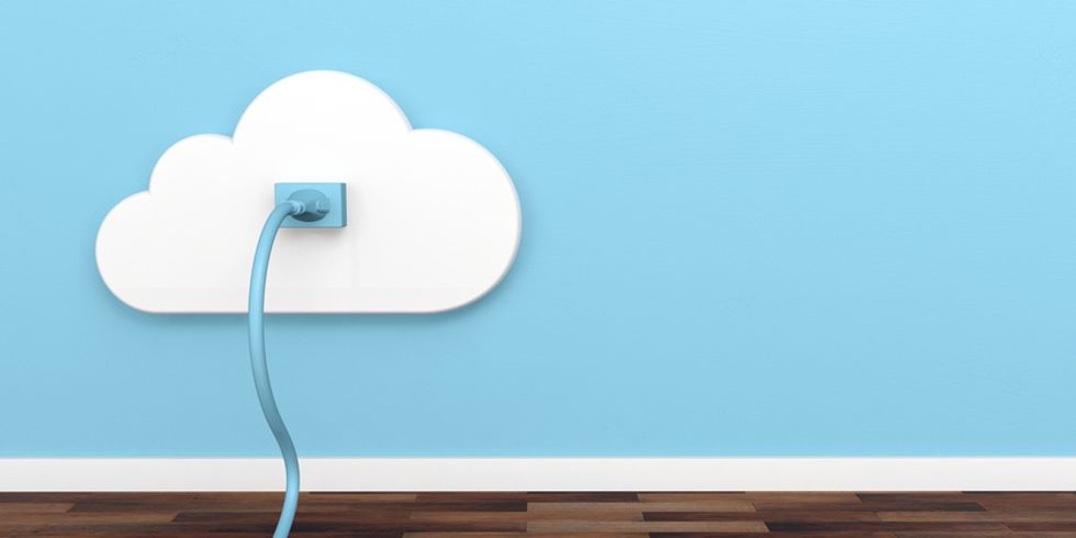 A white cutout of a cloud, with a blue plug coming out of it on a blue wall
