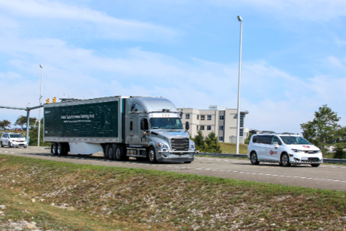 A semi-truck on the road with a Torc Robotics car in front and back