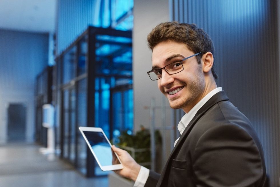 Young professional man smiling more at work and becoming happier in the workplace.