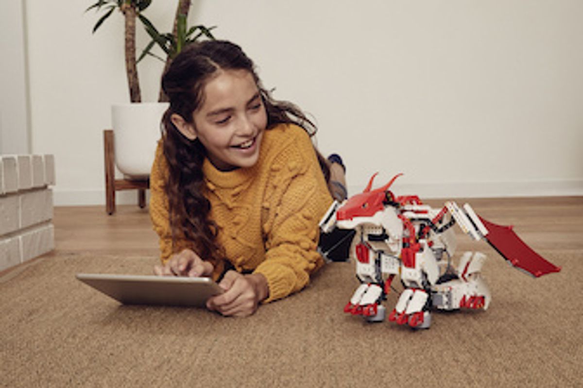 A child sitting on the ground next to UBTECH Jimu FireBot Kit, a build your own robot dragon