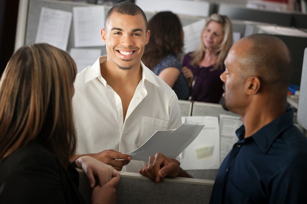 Young male office worker enjoying his first day at work and talking to his new co-workers.
