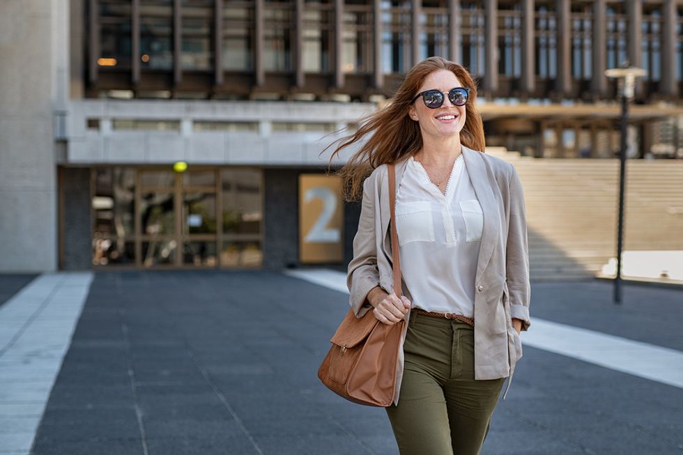 Smiling young female worker walking into work on her first day at a new office.