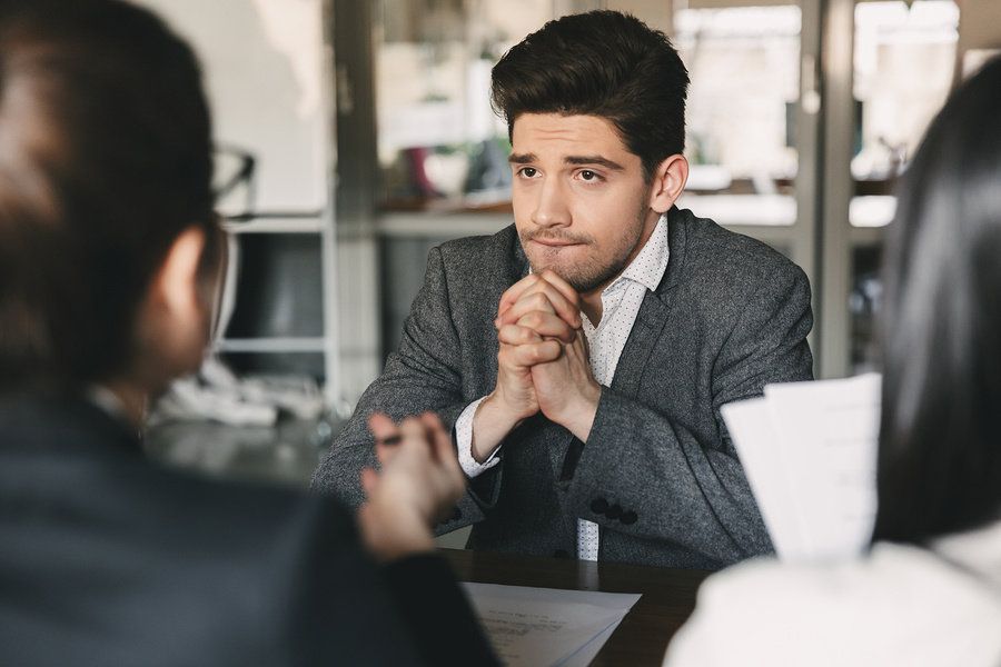 Young professional man debating whether or not he should turn down a job offer during a job interview.