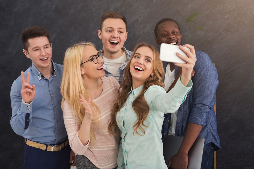 Co-workers keep things light in the office and take a selfie.