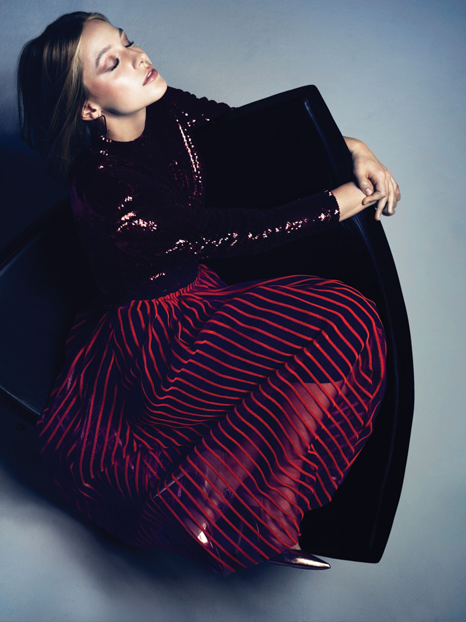 Supergirl's Melissa Benoist sits wearing a shiny dark purple top and red striped velvet skirt.