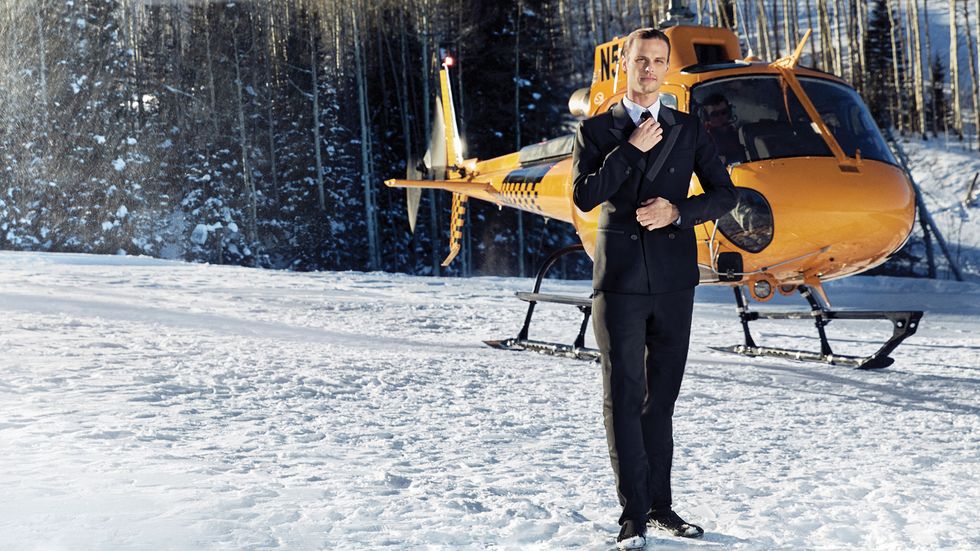 Matthew Gray Gubler on mountain top in a tuxedo with a helicopter