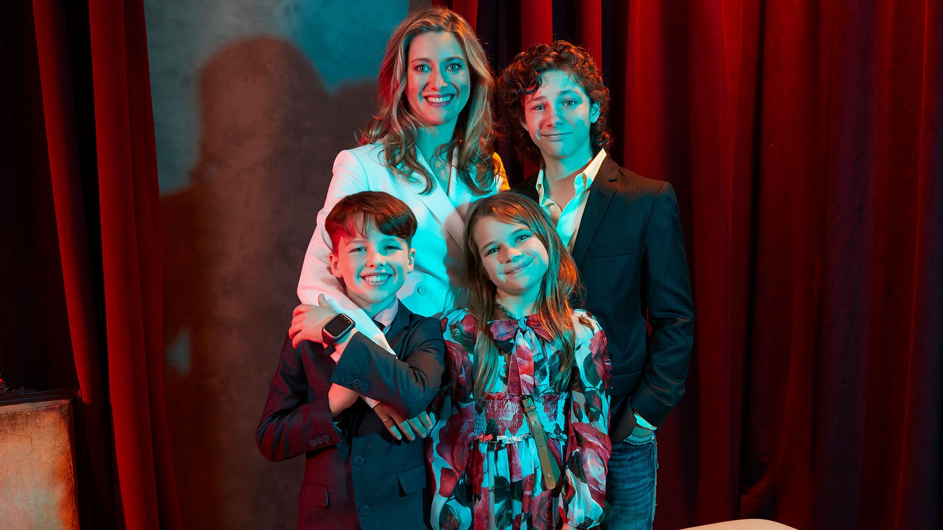The cast of Young Sheldon stands in front of a red velvet curtain.