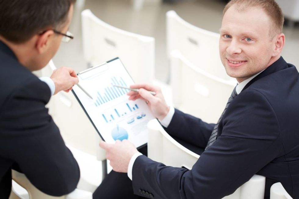 Statistician going over data with a business man in an office.