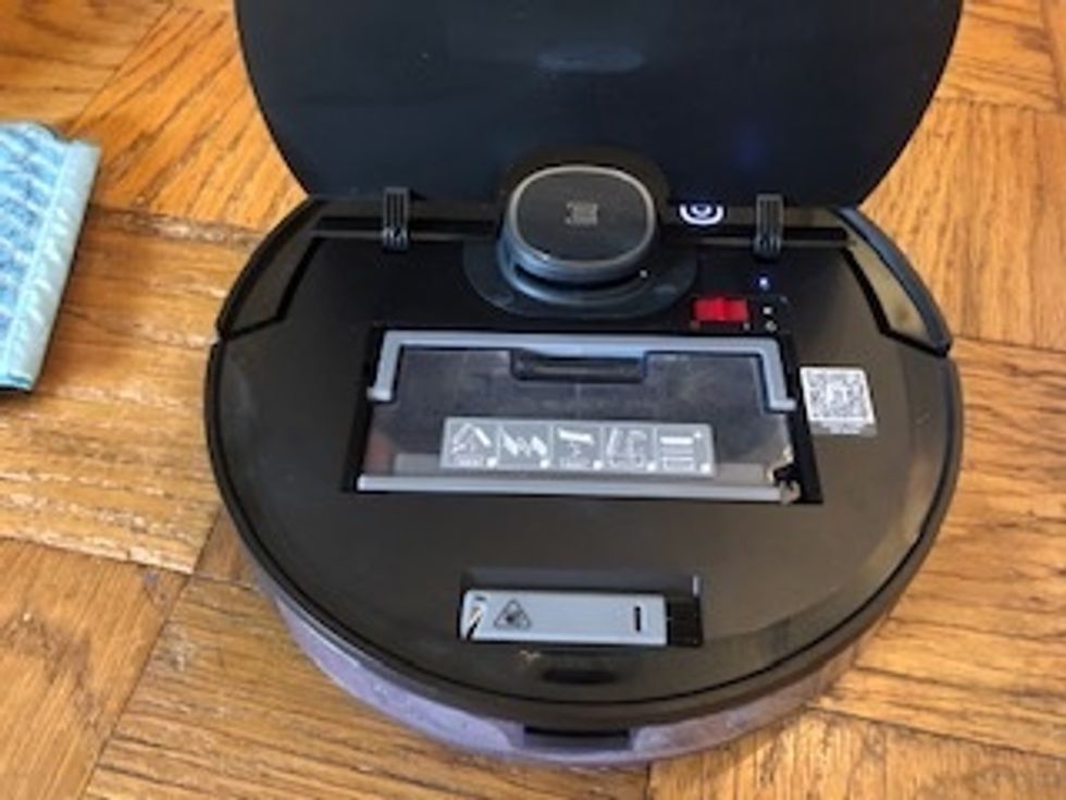 A robot vacuum open with a clear bin visible inside
