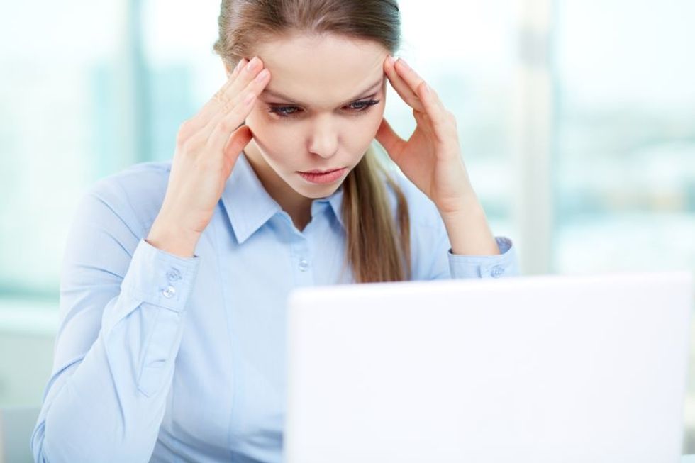 Frustrated business woman looking at her computer, thinking of ways to upskill at work and become happier at work.